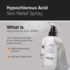 Eine behandschuhte Hand hält eine Flasche des Minimalist HOCl Skin Purifying Spray 150ppm vor einem grauen Hintergrund mit Text.