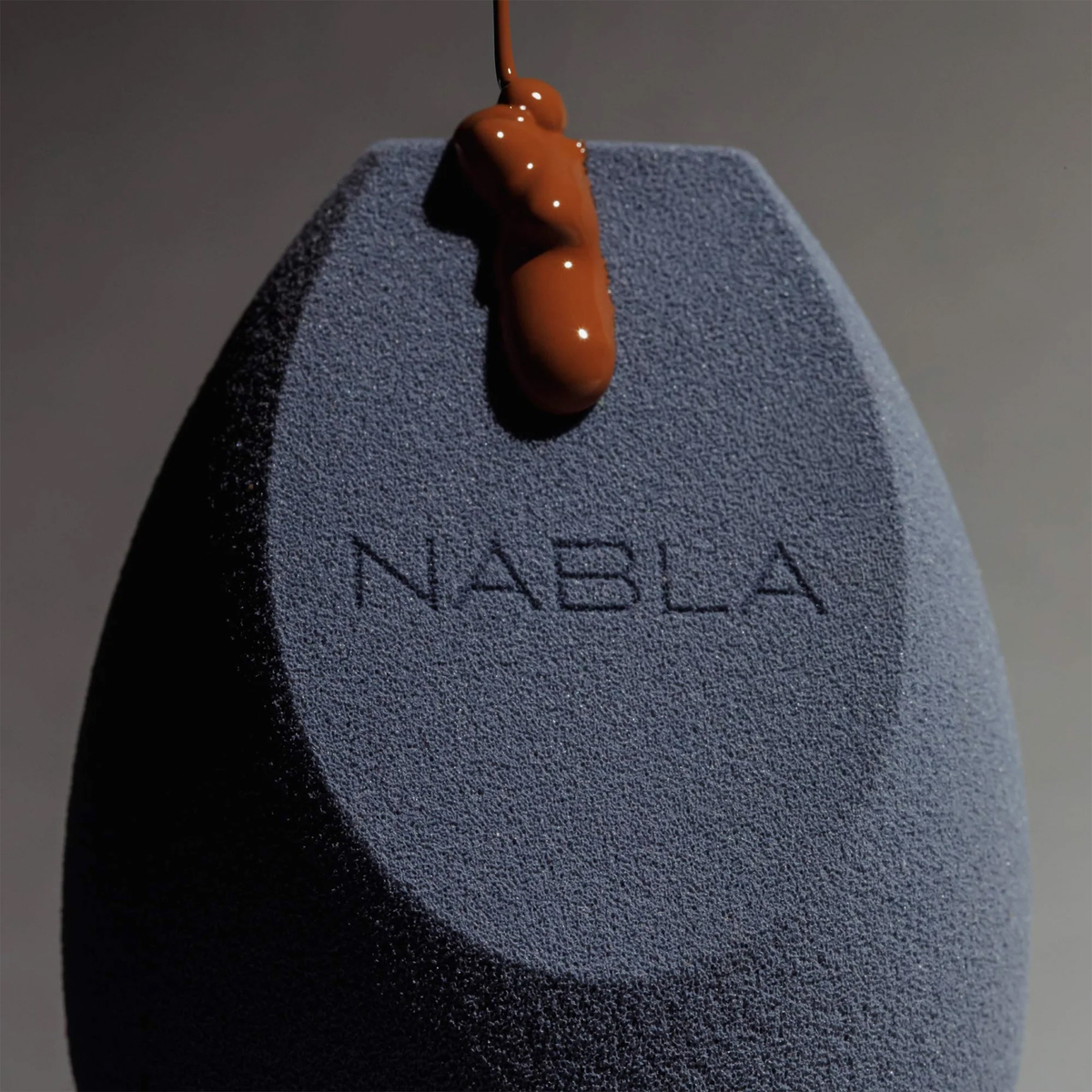 Ein NABLA Cosmetics Blended-up Multi-Angled Sponge, auf den flüssige Foundation gegossen wird.
