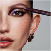 Nahaufnahme eines Auges mit auffälligem lila Augen-Make-up, während ein NABLA Cupid’s Arrow Stift als Eyeliner am äußeren Augenwinkel angesetzt wird.