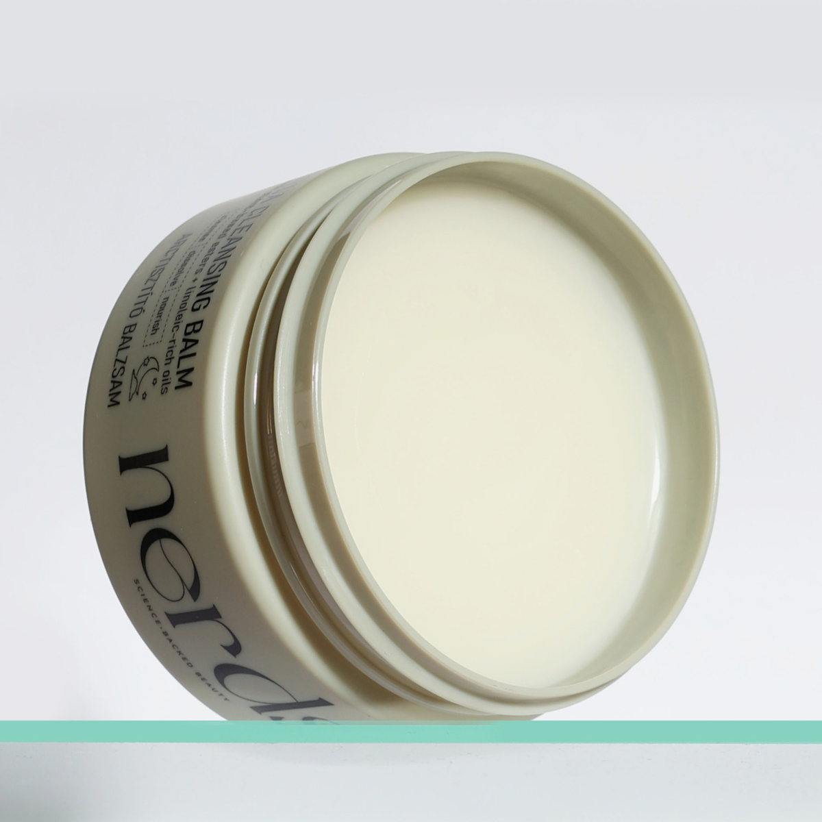 Ein geöffneter Tiegel NERDS. Centella Cleansing Balm wird vor einem schlichten weißen Hintergrund gezeigt.