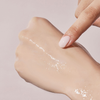 Ein Finger trägt das No.4 Collagen 73% Pudding Serum von numbuzin - eine klare, glänzende Flüssigkeit - vor einem hellen Hintergrund auf den Handrücken auf.