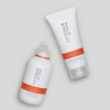 Zwei „Philip Kingsley Re-Moisturizing Shampoos“ mit weißen Flaschen und orangefarbenen Etiketten auf hellgrauem Hintergrund.