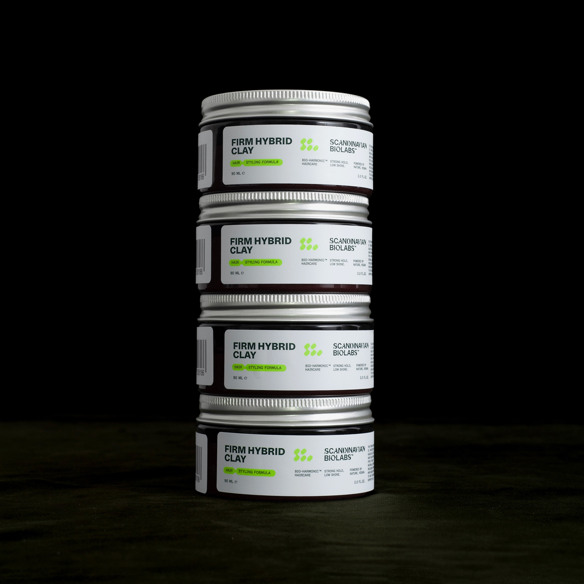 Vier Tiegel des Scandinavian Biolabs Firm Hybrid Clay sind vor einem dunklen Hintergrund gestapelt.