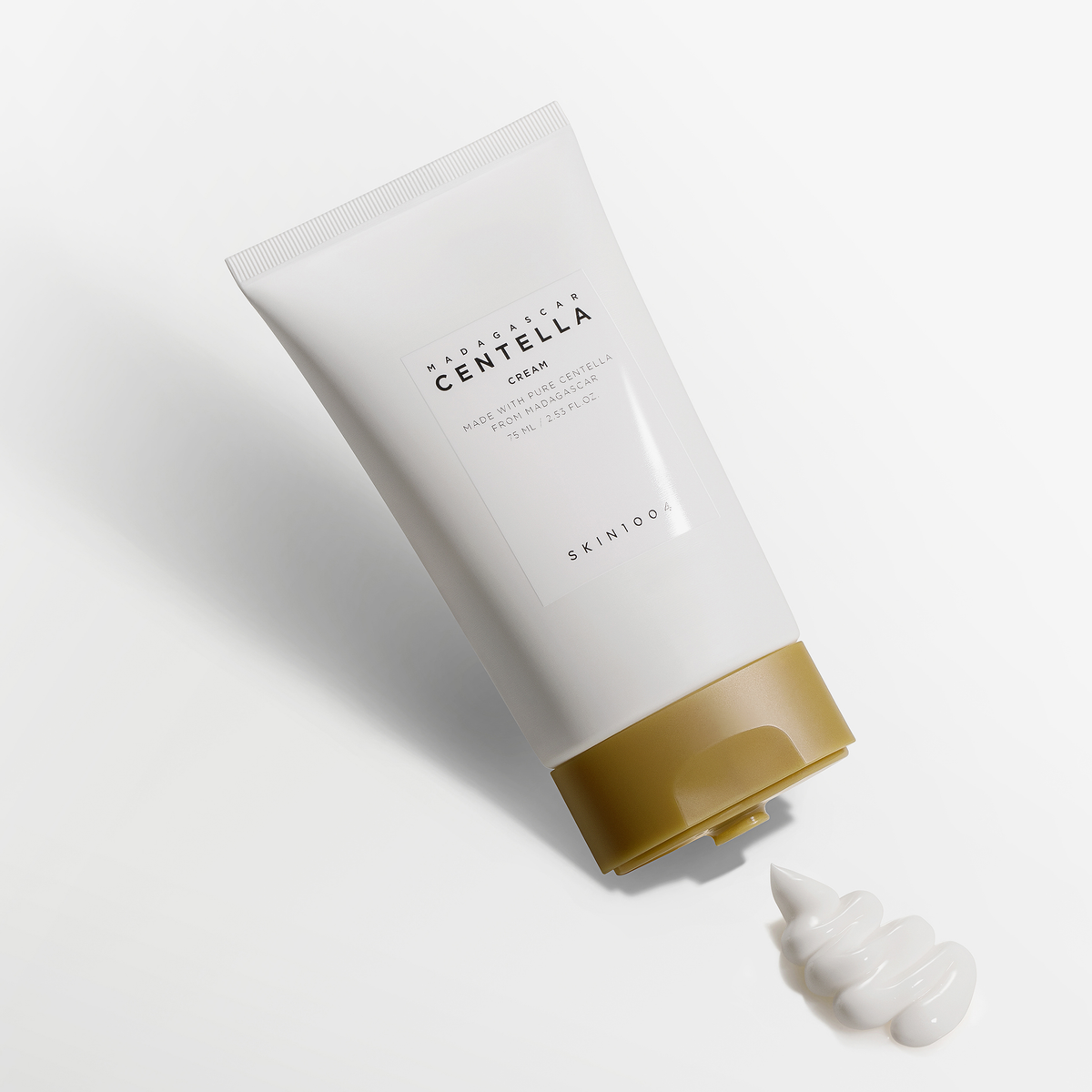 Eine Tube SKIN1004 Madagascar Centella Cream mit ausgedrückter Creme auf einer weißen Fläche.