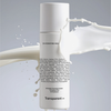 Eine Flasche Transparent Lab C4 Hydrating Milky Toner mit einem Strudel aus milchiger Flüssigkeit drum herum.
