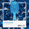 Kleine Bürste des UNbrush Glitter Duo Set Sapphiere Blue auf blauen Sapphirsteinen abgebildet.