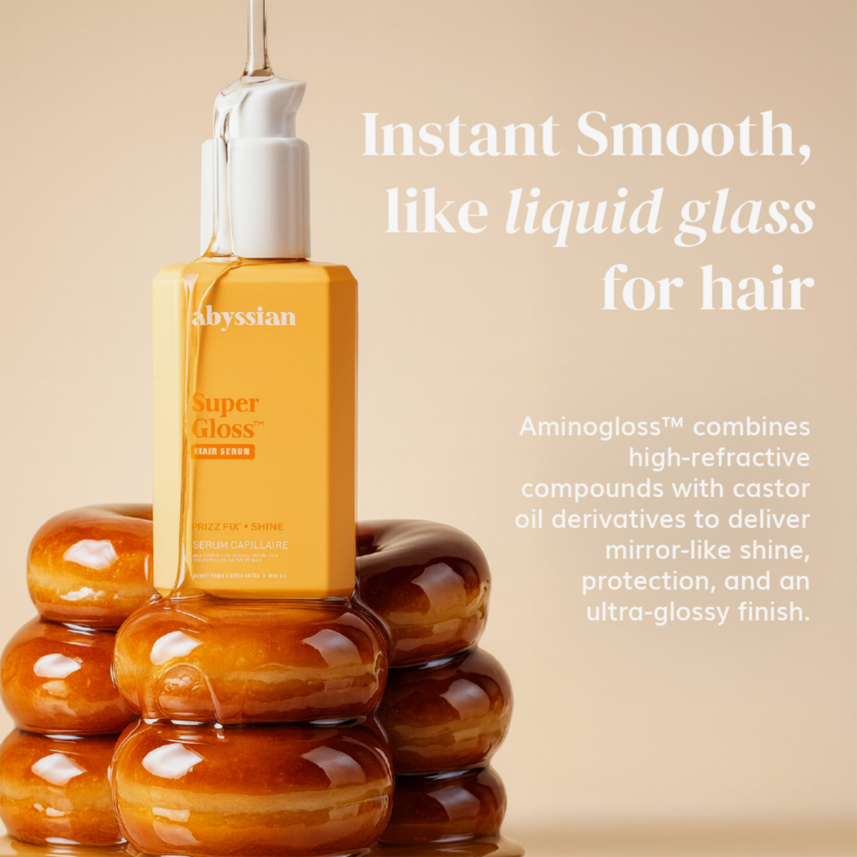 Das „Abyssian Supergloss Hair Serum“ thront auf einem Stapel Donuts und hebt im Text die glanzverstärkenden und glättenden Eigenschaften hervor.