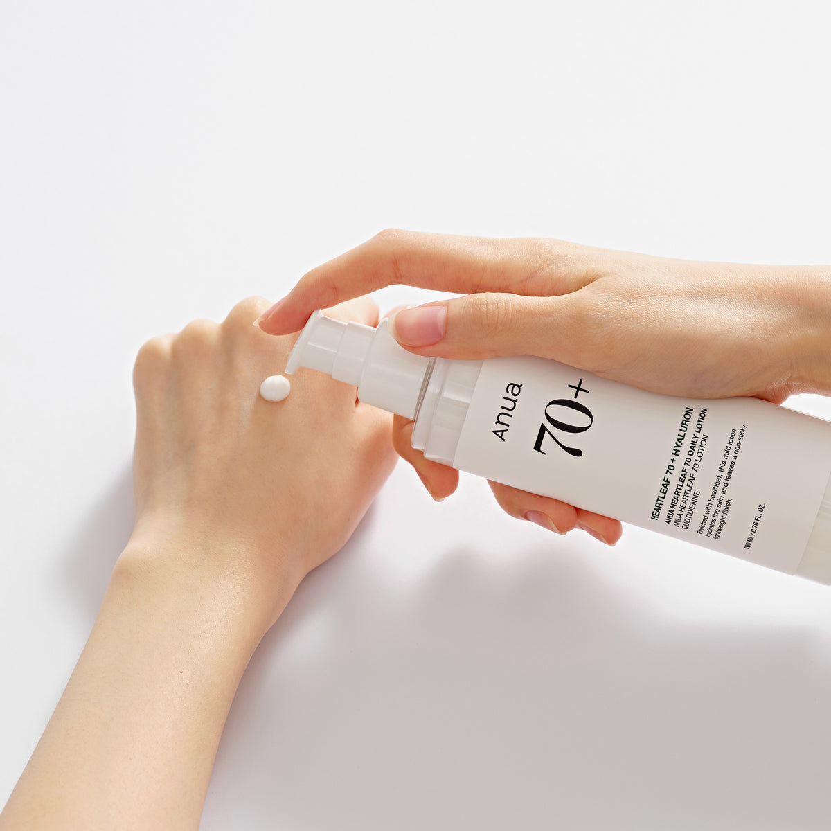 Eine Hand pumpt Lotion aus einer weißen Flasche mit der Aufschrift „Heartleaf 70 Daily Lotion“ auf den Handrücken der anderen Hand.