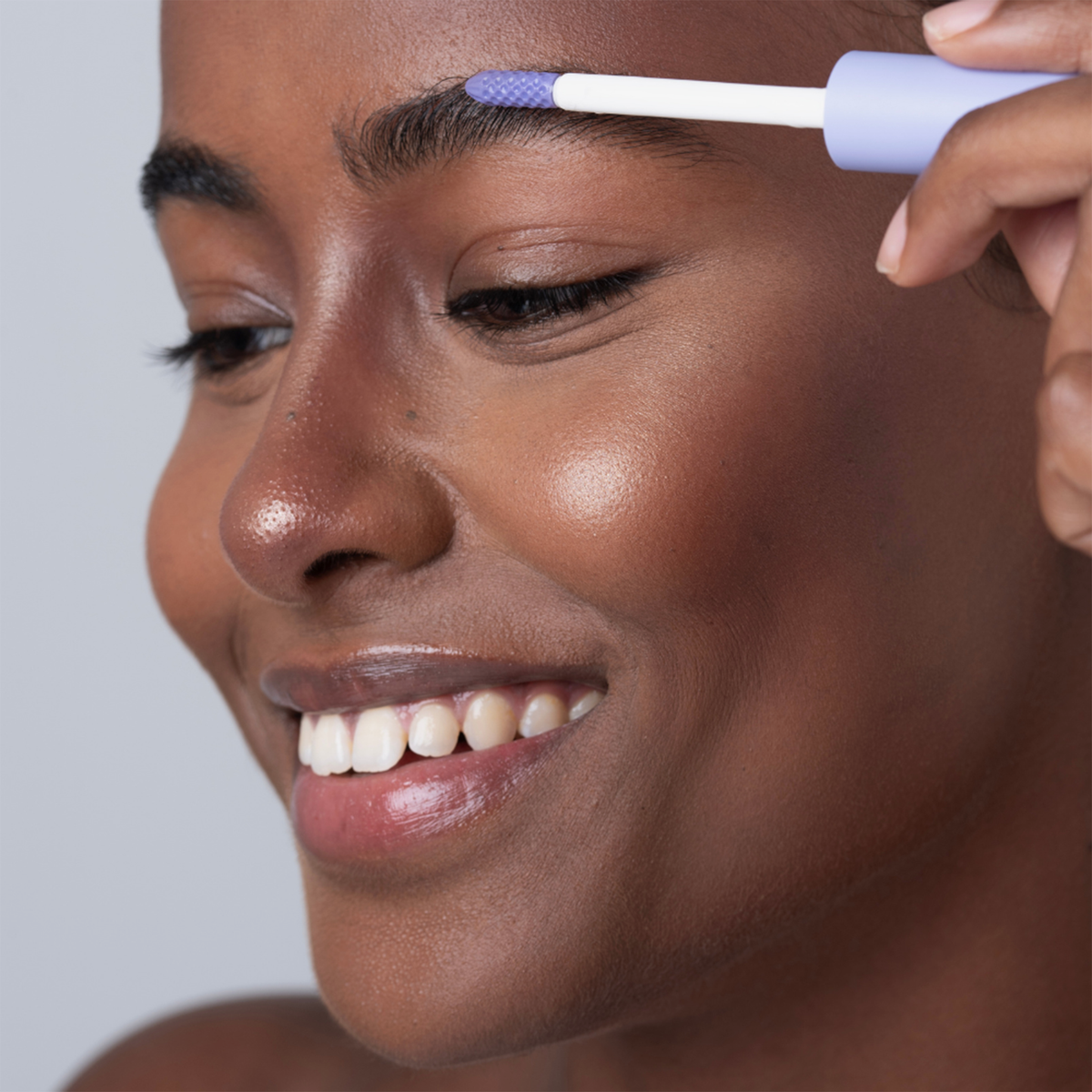 Eine lächelnde Person verwendet das BLONDESISTER 2 IN 1 EYES FIRST LASH&BROW SERUM, um ihre Augenbrauen zu pflegen.