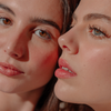 Die Models tragen „BLONDESISTER 2 IN 1 – IT’S UP TO YOU: LIP OR CHEEK“ und präsentieren sich mit natürlichem Make-up und rosigen Wangen im sanften Tageslicht.