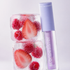 Zwei Eiswürfel mit Beeren, daneben ein lilafarbenes „BLONDESISTER 3 IN 1 CUTE LIPPY LIP OIL“.