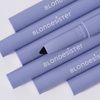 Sechs lavendelfarbene BLONDESISTER 3-in-1-Lidschatten-, Eyeliner- und Kajalstifte, von denen einer ohne Kappe ist, sodass die schwarze Spitze sichtbar ist.
