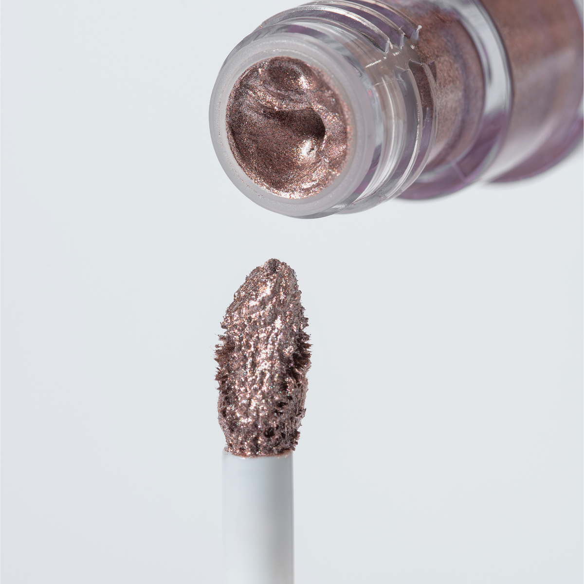 Eine Nahaufnahme des roségoldenen Applikators und der geöffneten Tube des „BLONDESISTER GLOWEYE EYESHADOW“ vor einem hellen Hintergrund.