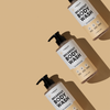 Drei Flaschen breakout+aid Breakout Body Wash, diagonal auf einem beigen Hintergrund angeordnet.