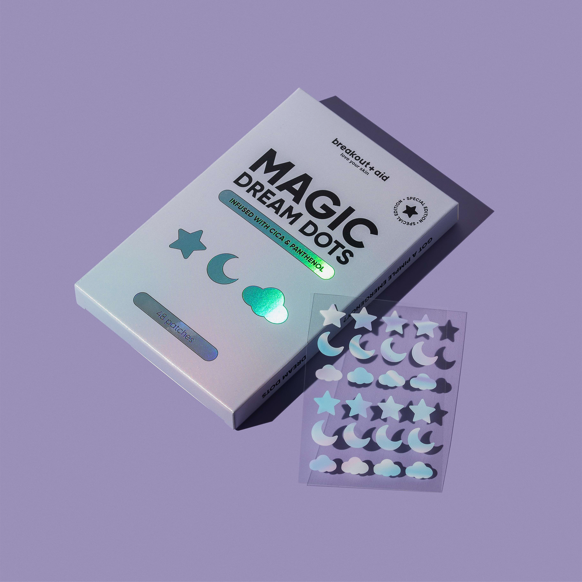 Eine Schachtel Magic Dream Dots-Akne-Pflaster neben einem Bogen mit Aufklebern in Form von Sternen, Monden und Wolken.