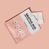 Eine teilweise geöffnete Verpackung der Breakout+Aid Salicylic Acid Clarifying Mask mit Text und Symbolen, auf denen die Inhaltsstoffe aufgeführt sind.