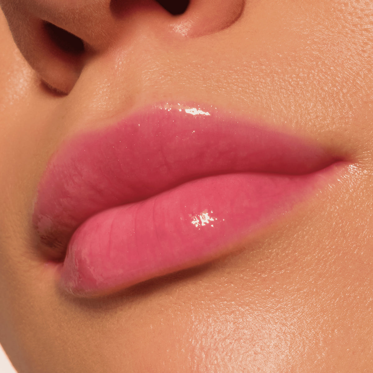Nahaufnahme glänzender Lippen in einem zarten Rosaton, geschminkt mit dem Catrice Colour Cushion Juicy Lip Oil für ein glänzendes Finish.