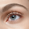 Nahaufnahme eines blauen Auges mit langen Wimpern, die mit Catrice Cosmetics TUBING Stay In Place Volume Mascara 010 getuscht sind.