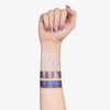 Eine Hand mit schillernden Nägeln zeigt vier Colorfix Stix Infinity Swatches von Danessa Myricks Beauty auf einem hellen Unterarm.