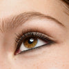 Nahaufnahme eines braunen Auges mit präzisem schwarzen Eyeliner am unteren Wimpernkranz und langen, definierten Wimpern.