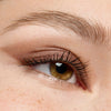 Nahaufnahme eines haselnussbraunen Auges mit langen Wimpern und natürlichem braunen Lidschatten, mit definierten Linien.