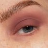 Eine Nahaufnahme eines blauen Auges mit dem matten mauvefarbenen Lidschatten The Single von LH Cosmetics und einer natürlichen, gepflegten Augenbraue.