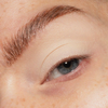 Eine Nahaufnahme eines Auges mit natürlichem Make-up unter Verwendung von The Single von LH Cosmetics, mit gepflegten Augenbrauen und leichten Sommersprossen.