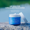 Geöffneter blauer Tiegel mit Lumene Nordic Hydra [LÄHDE] Intense Hydration Moisturizer steht auf einem Stein, darüber Info zur recyclebaren Verpackung.