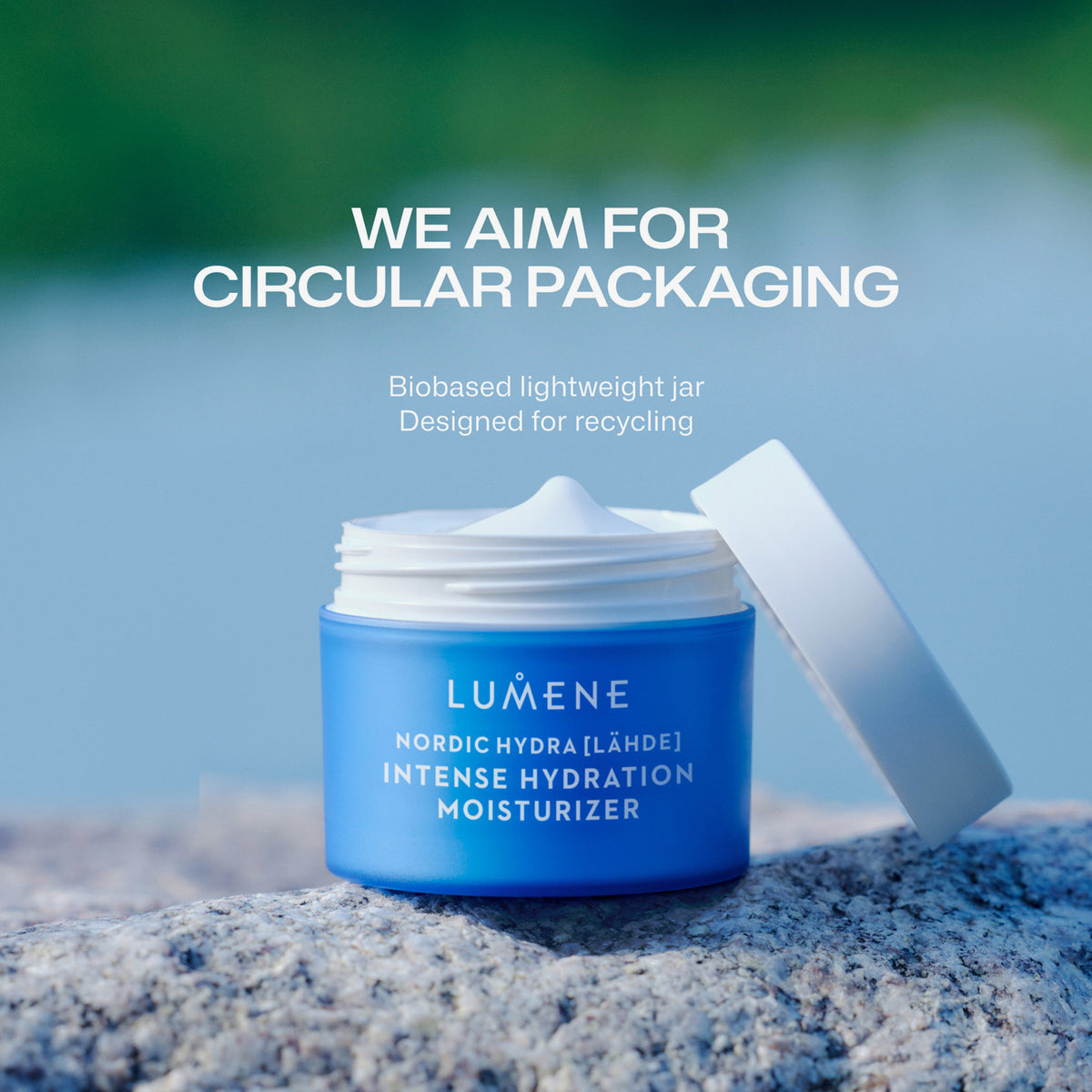 Geöffneter blauer Tiegel mit Lumene Nordic Hydra [LÄHDE] Intense Hydration Moisturizer steht auf einem Stein, darüber Info zur recyclebaren Verpackung.