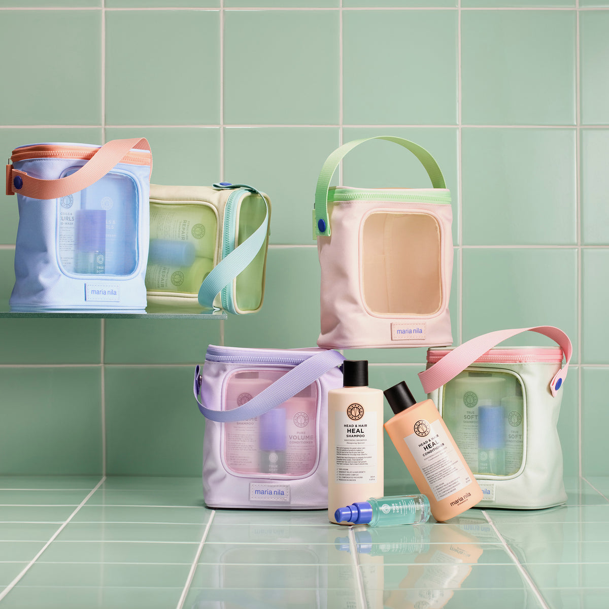 Mehrere Maria Nila Beauty Bags 2025 in Pastelltönen; mit Haarpflege Sets dargestellt auf mintgrünem Fliesenhintergrund. 