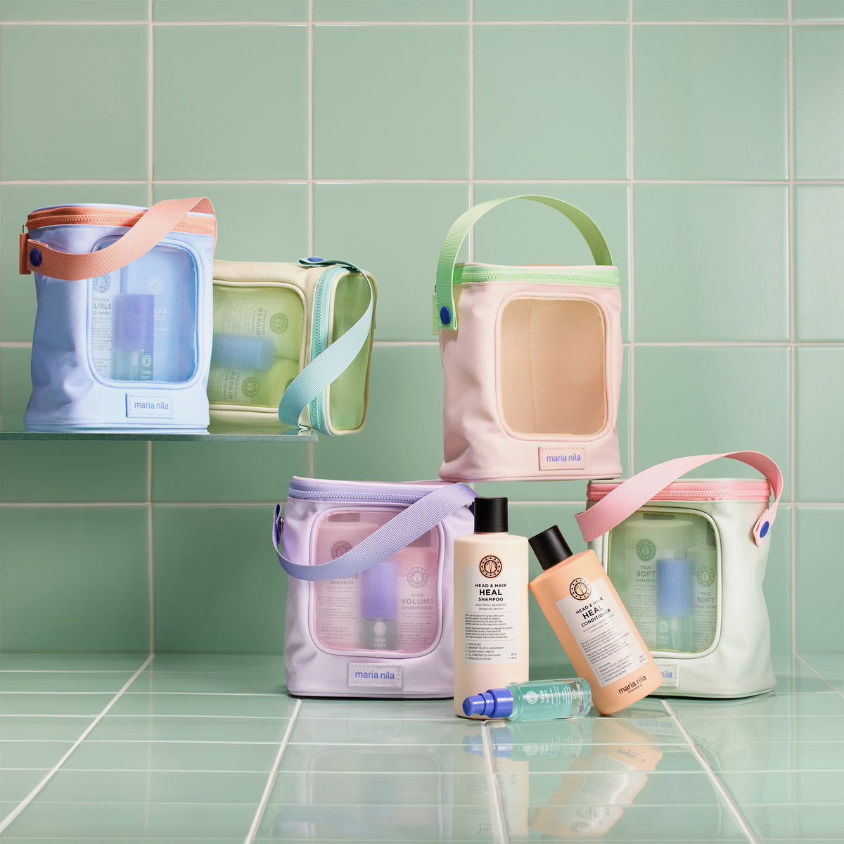 Mehrere Maria Nila Beauty Bags 2025 in Pastelltönen; mit Haarpflege Sets dargestellt auf mintgrünem Fliesenhintergrund.