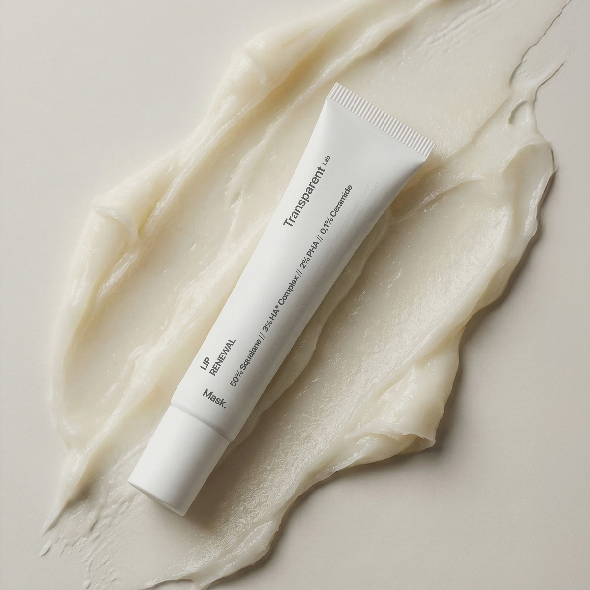 Transparente Lab Lip Renewal-Tube auf einem Cremeabstrich, von oben gesehen vor einem neutralen Hintergrund.