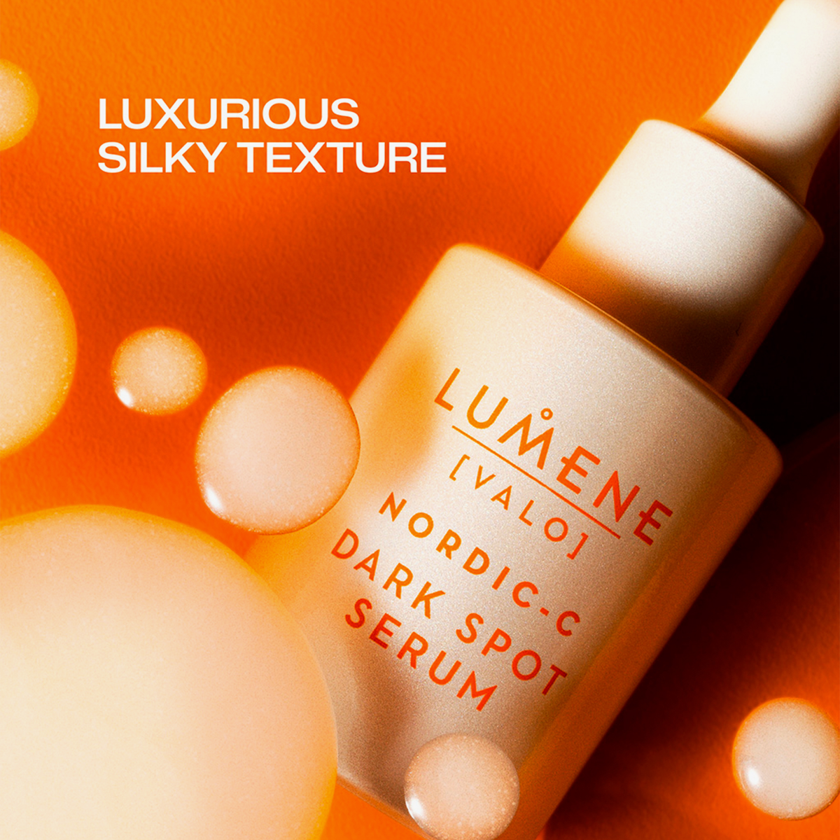 Eine Flasche Lumene Nordic-C Dark Spot Serum mit Blasen auf orangefarbenem Hintergrund.