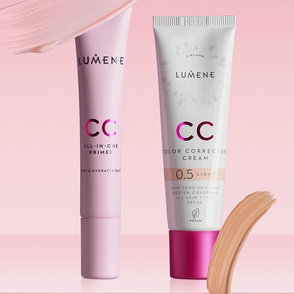 Zwei Lumene CC All-In-One Primer-Tuben auf rosa Hintergrund mit Make-up-Strichen oben und unten.