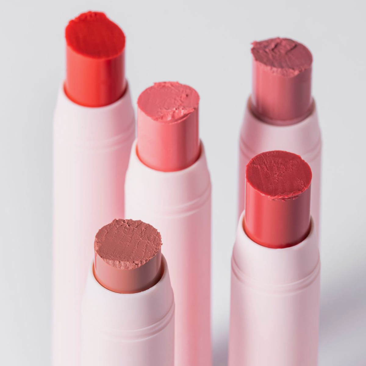 Fünf Tuben „BLONDESISTER 2 IN 1 IT’S UP TO YOU LIP OR CHEEK“ in Rosa- und Rottönen stehen aufrecht, die strukturierten Spitzen sind sichtbar.