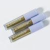 Drei goldene Tuben „BLONDESISTER GLOWEYE EYESHADOW“ mit hellvioletten Verschlusskappen sind diagonal auf einem weißen Hintergrund angeordnet.