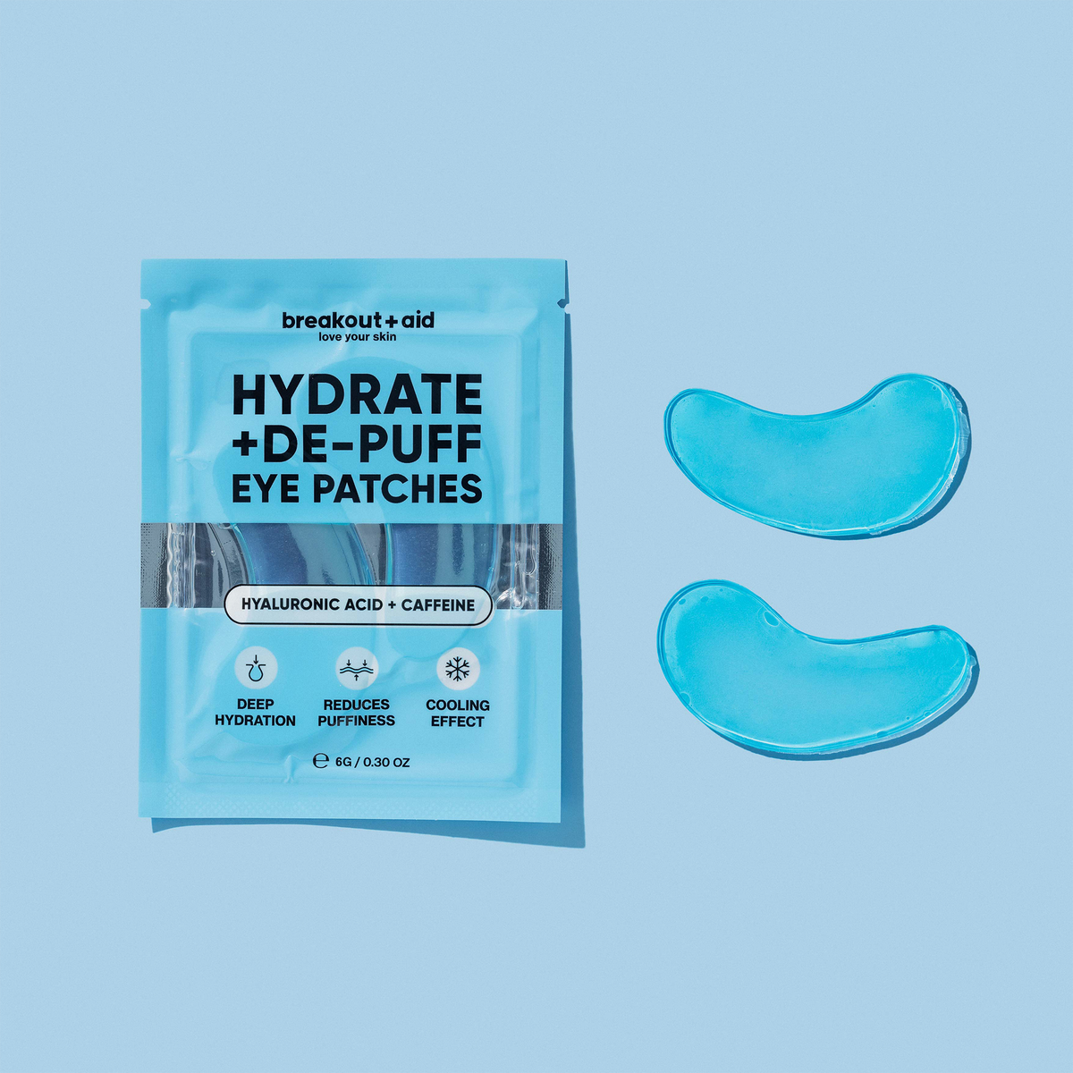 Eine hellblaue Packung Hydrate + De-Puff Eye Patches neben zwei durchscheinend blauen Gelmasken für die Augenpartie.
