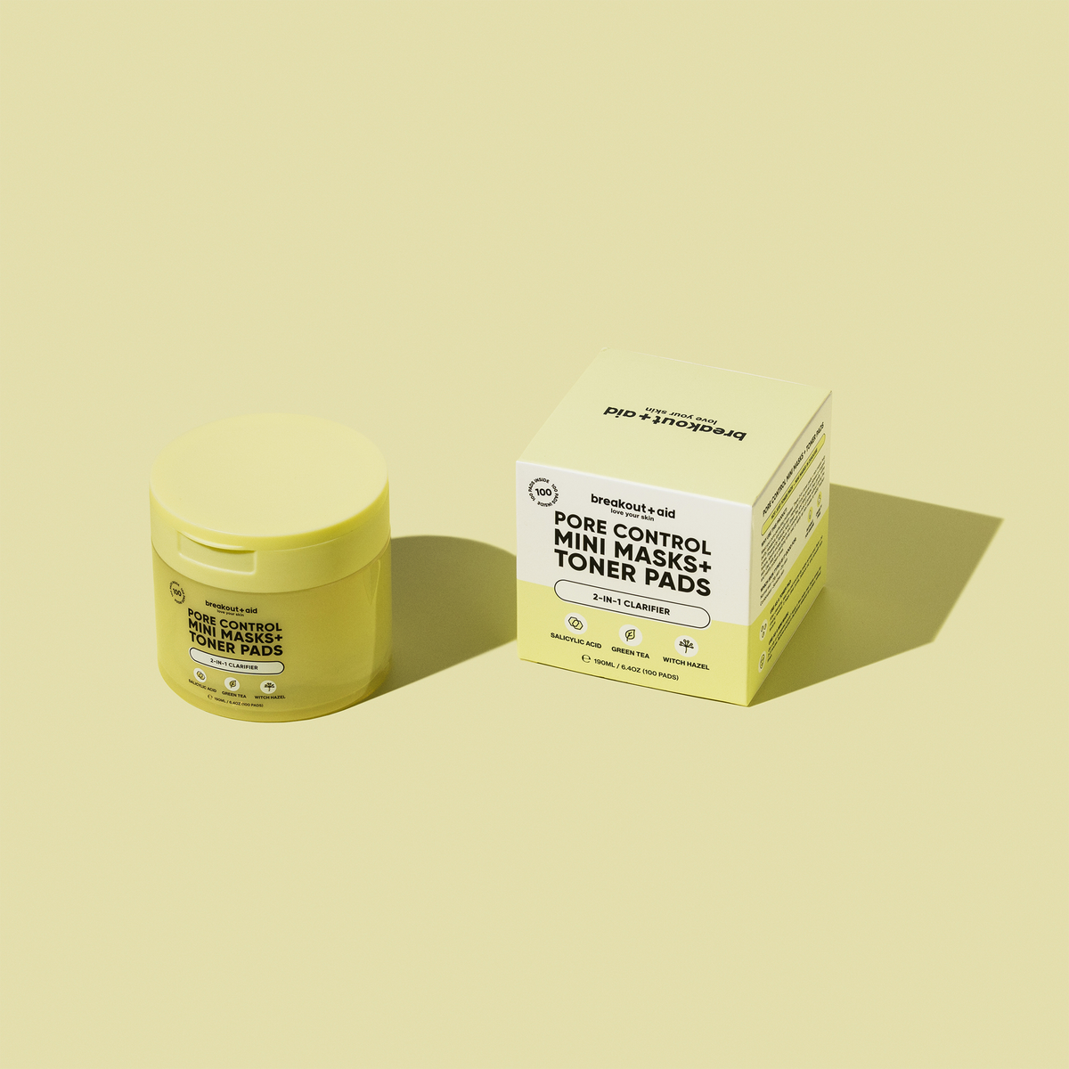 Ein gelbes Glas und eine dazu passende quadratische Schachtel mit breakout+aid Pore Control Mini-Masken + Toner-Pads.