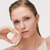 Frau, die die Pillow Plush Peptide Lip Mask 010 von Catrice Cosmetics in der Nähe ihrer Lippen hält und mit einem neutralen Blick in die Kamera schaut.