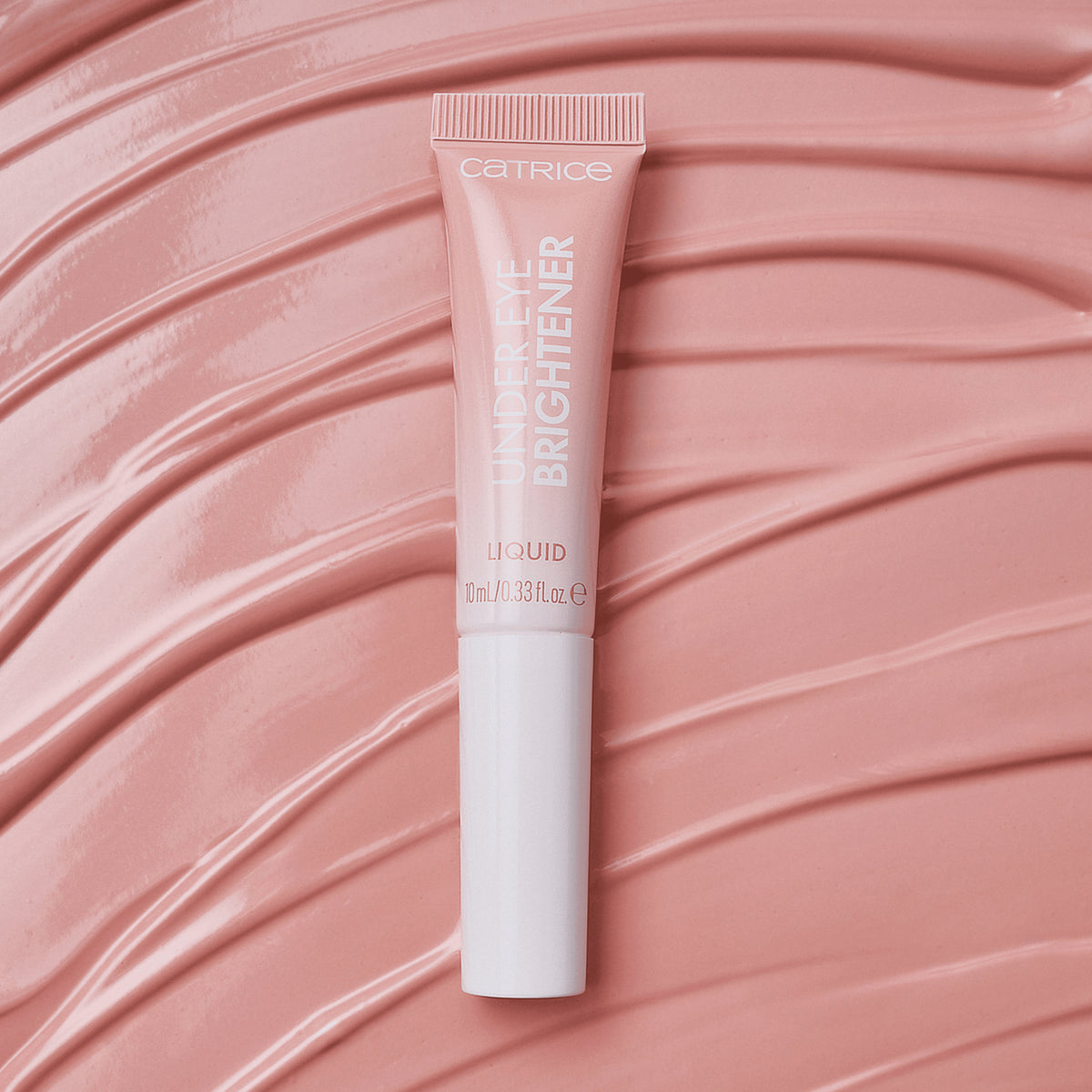 Eine Tube Catrice Cosmetics Under Eye Brightener Liquid auf einem strukturierten, hellrosa Hintergrund.