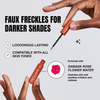 Eine Hand hält den Stift Freck Noir von Freck Beauty für künstliche Sommersprossen für dunklere Haut, dessen Eigenschaften und Vorteile in Text und Grafik dargestellt sind.