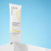 Die Geek & Gorgeous Zero Feel SPF 50 Sonnencreme steht aufrecht auf einer weißen Fläche mit blauem Hintergrund.