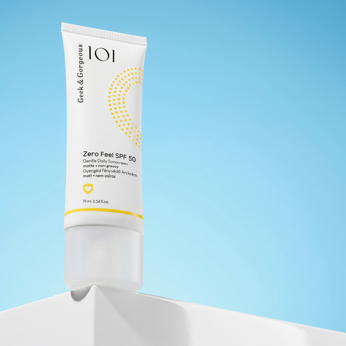 Die Geek & Gorgeous Zero Feel SPF 50 Sonnencreme steht aufrecht auf einer weißen Fläche mit blauem Hintergrund.