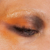 Eine Nahaufnahme eines geschlossenen Auges mit orangefarbenen und braunen Schimmerpartikeln aus der „Over The Garden Wall“-Palette von Lethal Cosmetics; die Wimpern sind zu sehen.