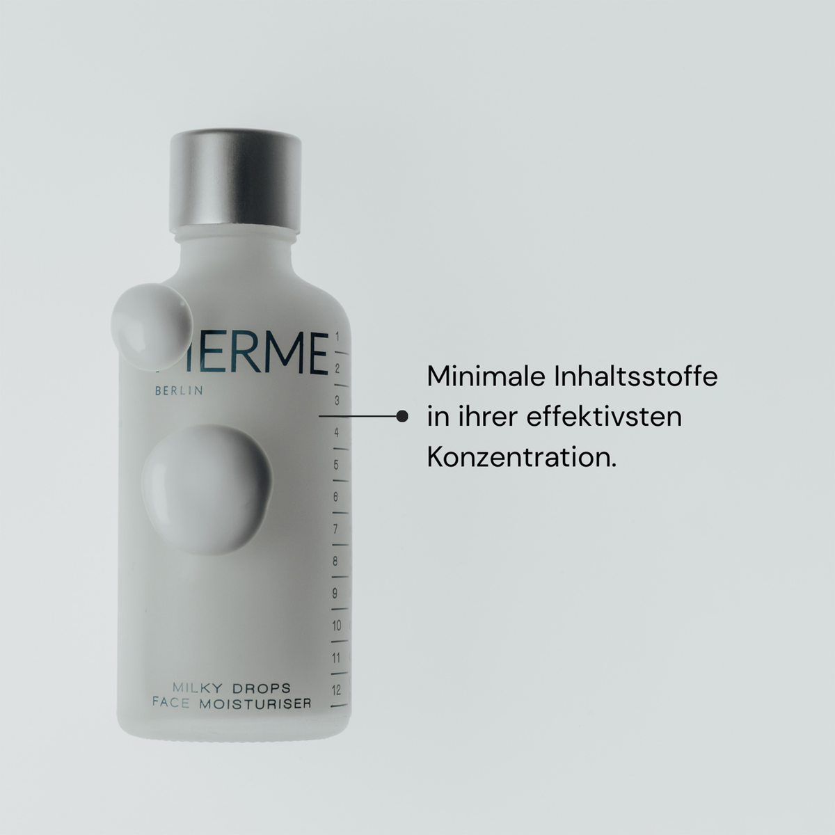 Auf der weißen Flasche mit der Aufschrift MERME Milky Drops Face Moisturiser steht ein deutscher Text über minimale, wirksame Inhaltsstoffe.