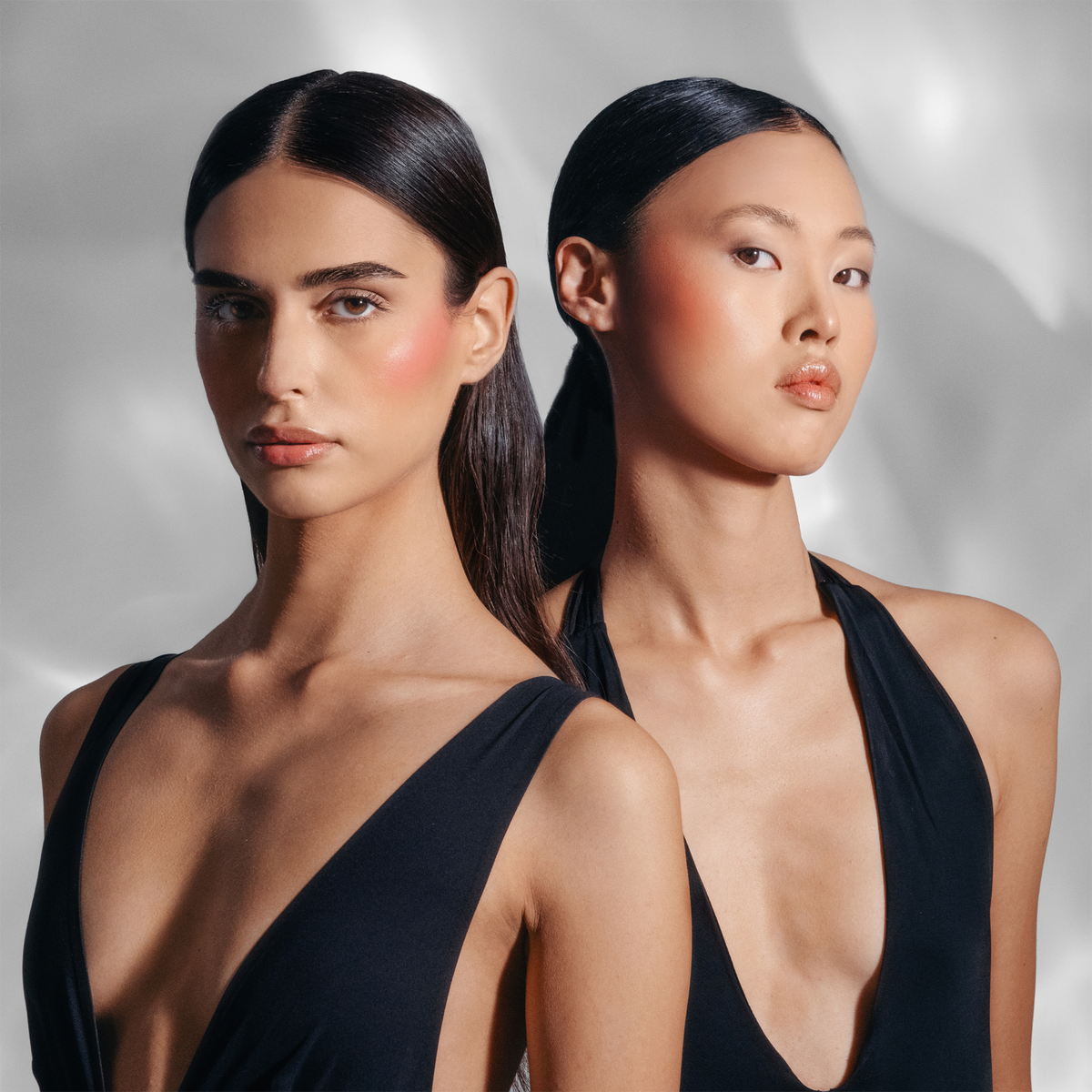 Zwei Frauen, die schwarze Oberteile und leuchtendes Make-up aus dem STELLAR GLOW CHRISTMAS KIT tragen, blicken in die Kamera.