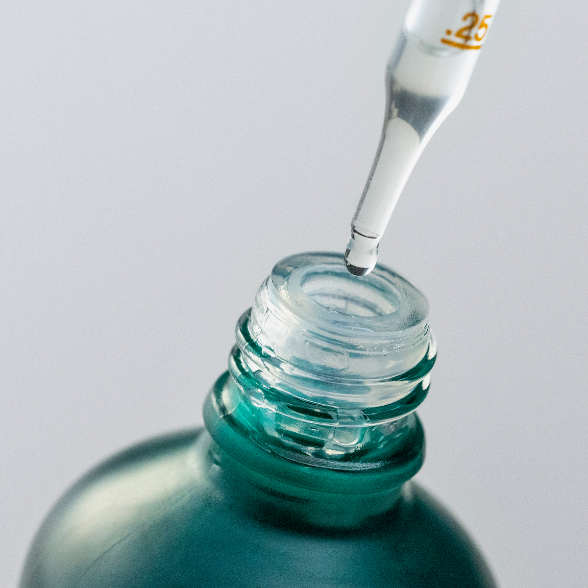 Vor einem hellen Hintergrund füllt eine Pipette „Density Preserving Scalp Drops“ von Philip Kingsley in eine grüne Flasche.