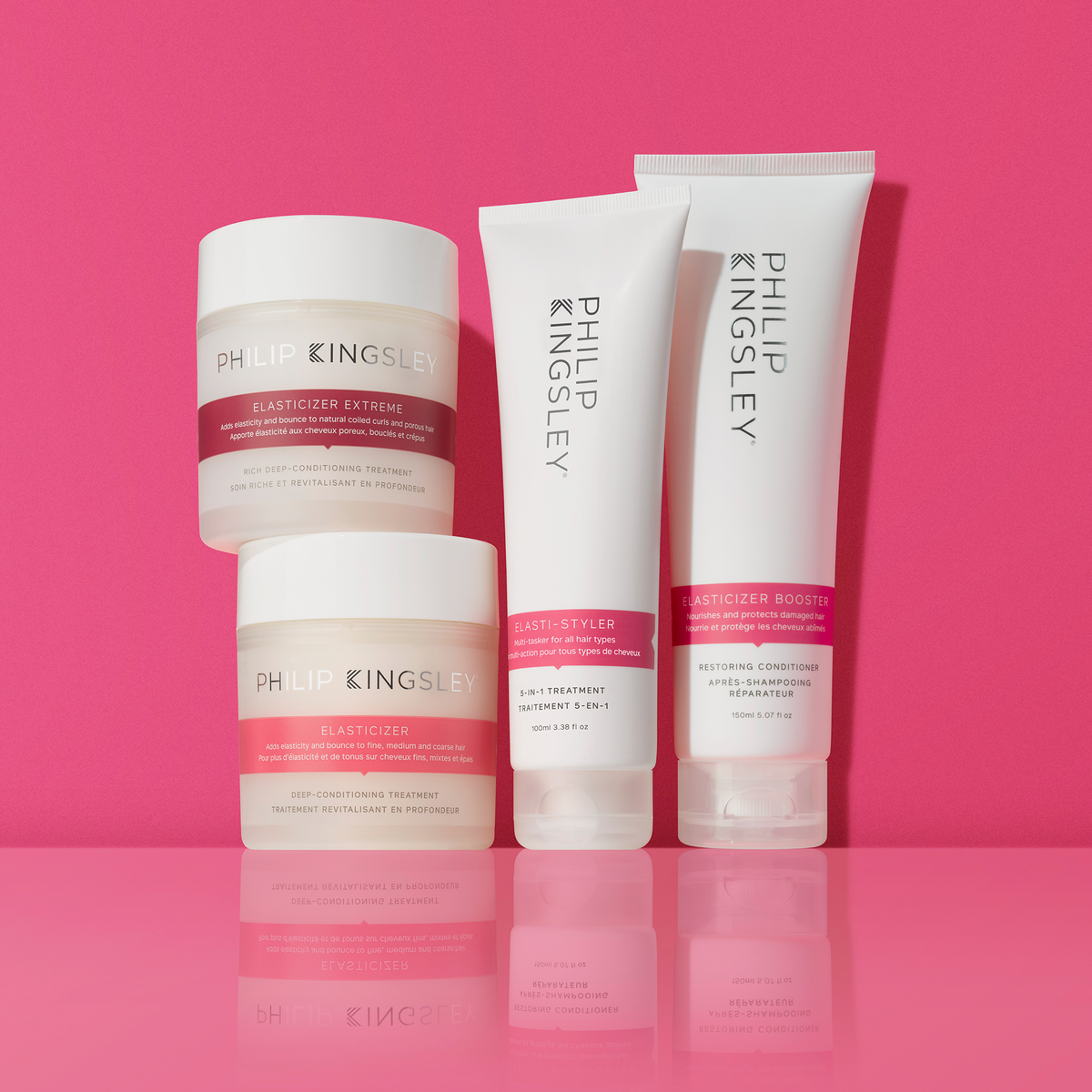 Die Haarpflegeprodukte der Marke „Philip Kingsley Elasticizer“ sind auf einer glänzenden rosa Fläche vor einem einfarbigen rosa Hintergrund angeordnet.