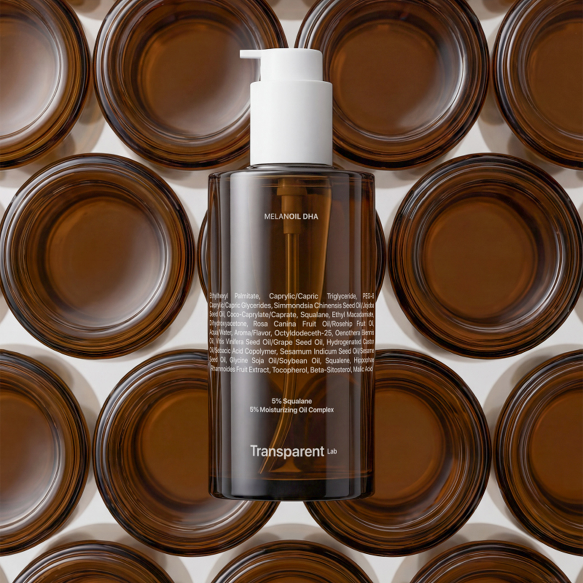 Eine Flasche Transparent Lab Melanoil DHA Serum ist mit braunem Muster der Flaschenunterseiten im Hintergrund abgebildet.