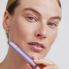 Eine Frau hält das XLASH Xbrow Sensitive Augenbrauenserum nahe an ihr Gesicht und betont damit ihre reine Haut und ihr dezentes Make-up.